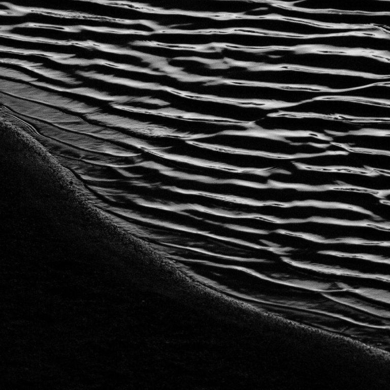 Rippled water meeting dark sand
