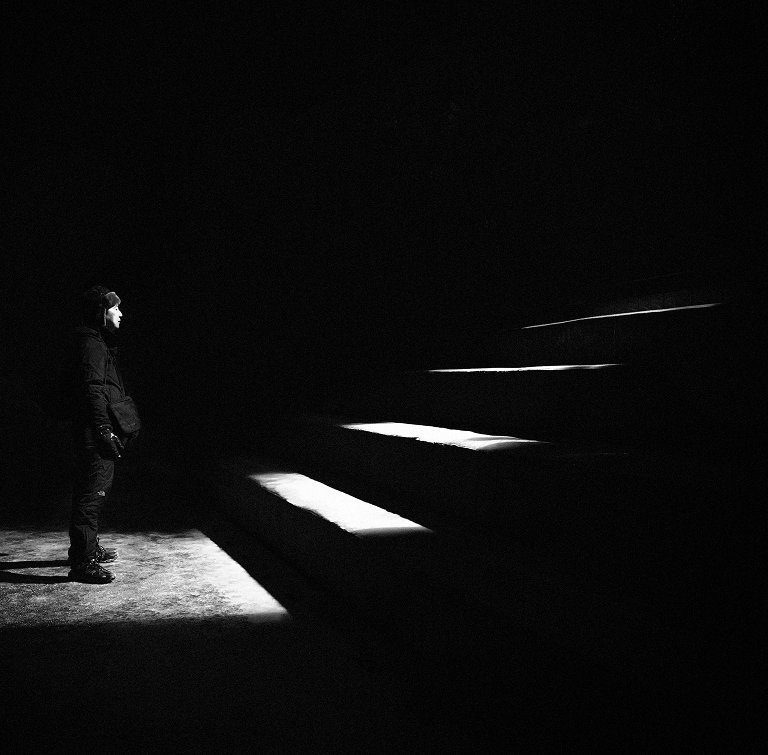 Figure in a shaft of light on dark stairs